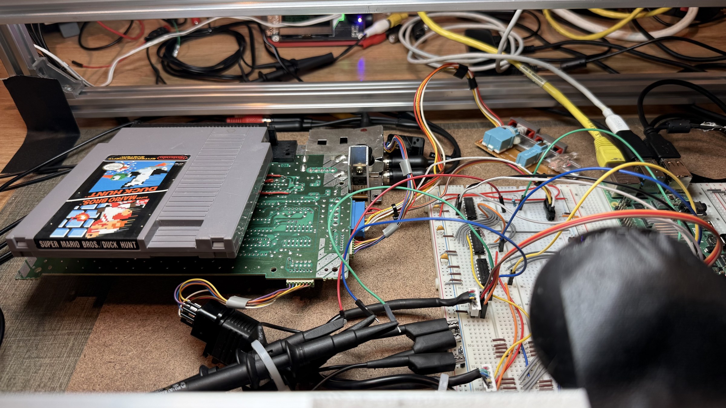 the console's side: the mainboard with the cartridge in, the modulator, the probe clips, the breadboards beyond
